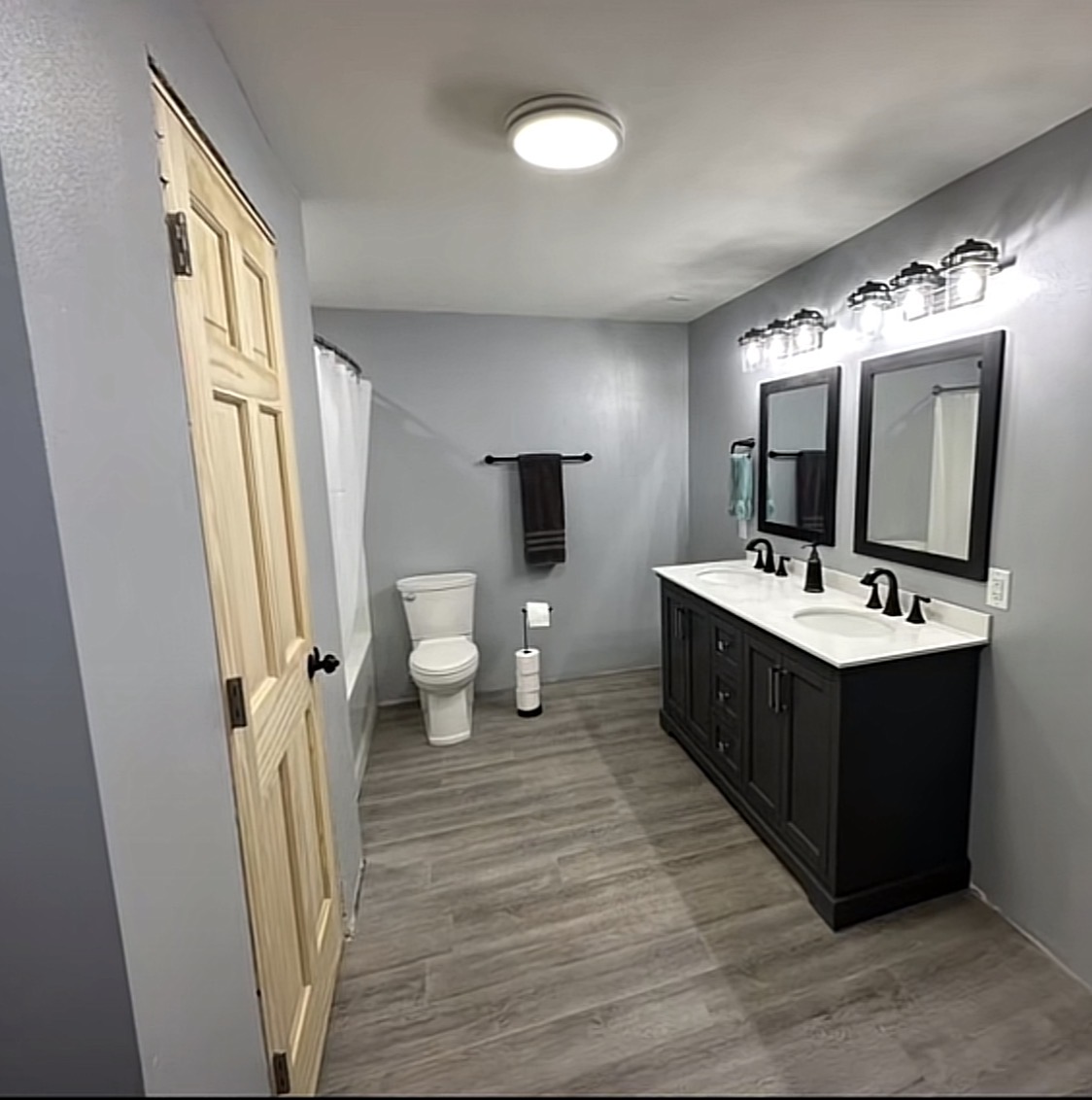 Finished gray bathroom with double vanity, black fixtures and durable flooring